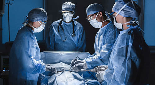 Doctor and Surgical Technologists around a patient getting surgery.