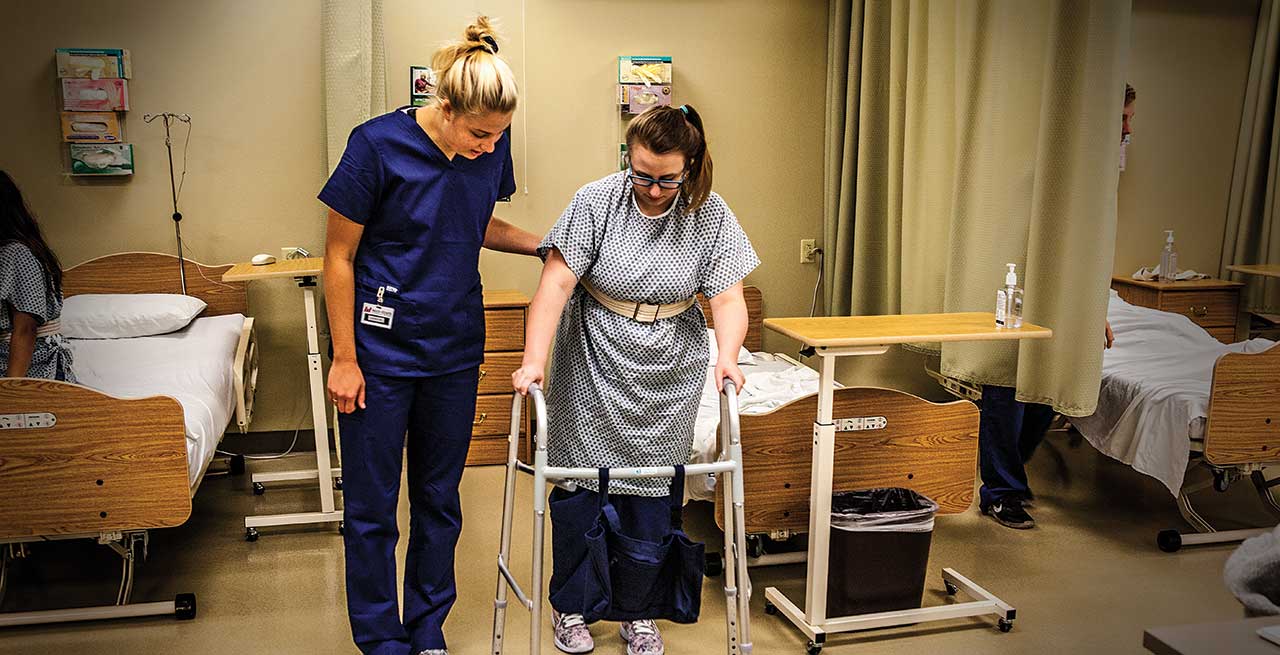 Nurse helping woman walk with a walker