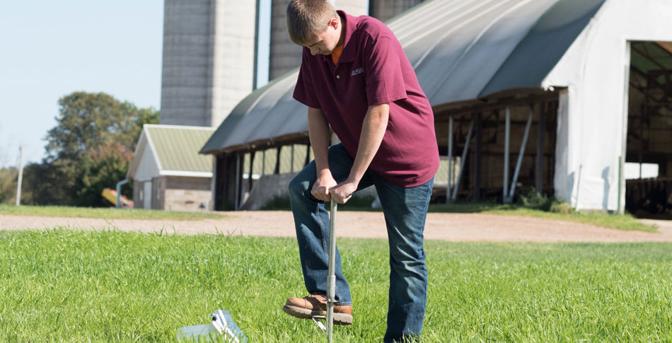 Man standing with his hands and one foot on tool pushing it into the ground