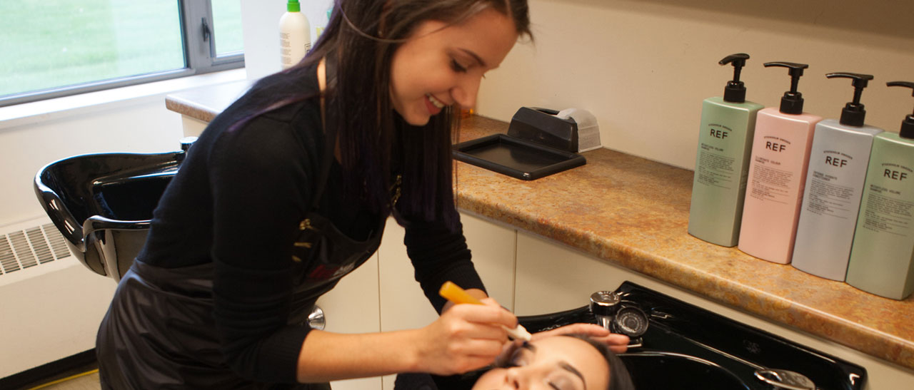 Cosmetology student providing waxing services to a customer in the salon.