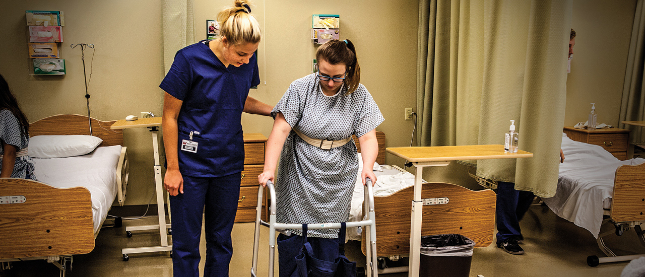 Female nursing assistant helps a patient who is walking with the aid of a walker