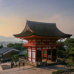 Image of a traditional Japanese structure at the top of a hill overlooking a scenic valley.