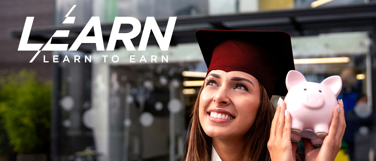 Woman in a graduation cap holding a piggy bank. L/EARN to earn