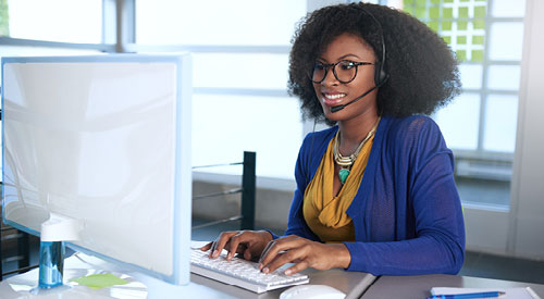 IT Computer Support Technician sitting at a computer wearing a headset
