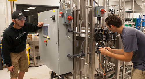 2 people working with industrial equipment taking readings