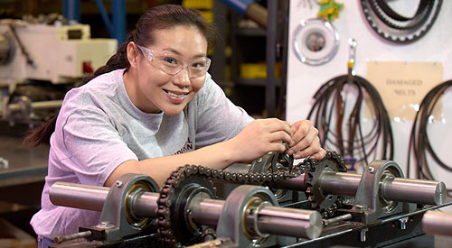 woman working with a chain connecting 2 rods with gears
