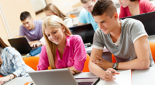 room of people sitting at long desks looking at laptops