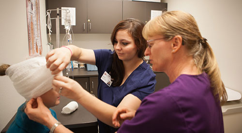 2 medical professionals removing a headwrap from a patient