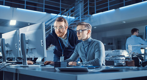 2 people sitting in front of monitors