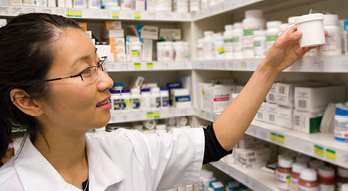 Pharmacy Technician grabbing medication off of the shelf