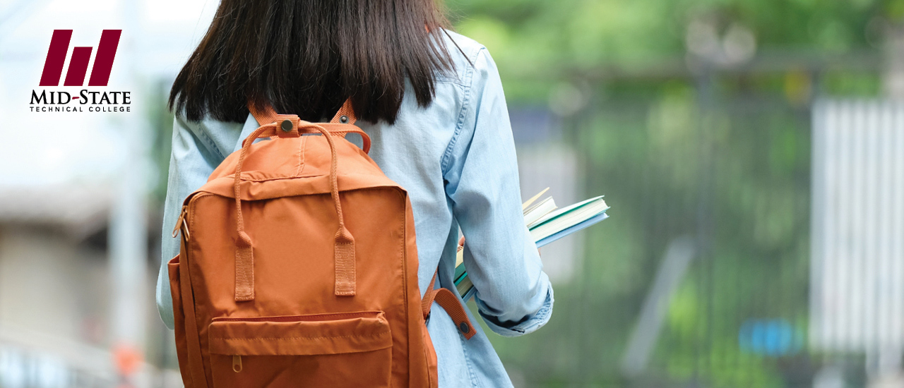 Woman wearing an orange backback carrying books walking away from the camera. Mid-State Technical College Logo in top left corner