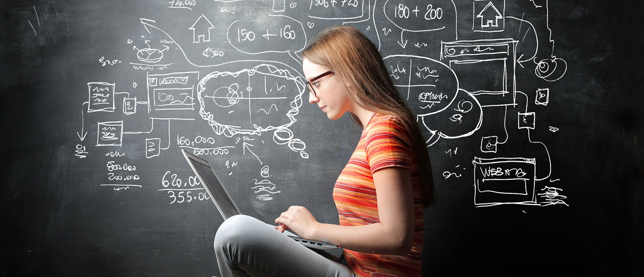Woman sitting in front of a chalkboard with a laptop