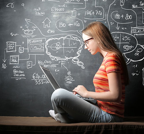 Woman sitting in front of a chalkboard with a laptop