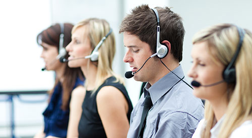 several people sitting at workstations wearing headsets talking to customers