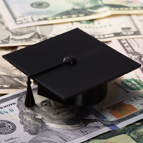 Graduation cap sitting on top of dollar bills