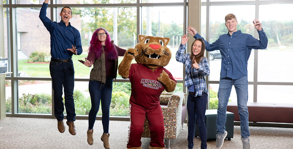 4 students jumping with Mid-State Mascot Grit