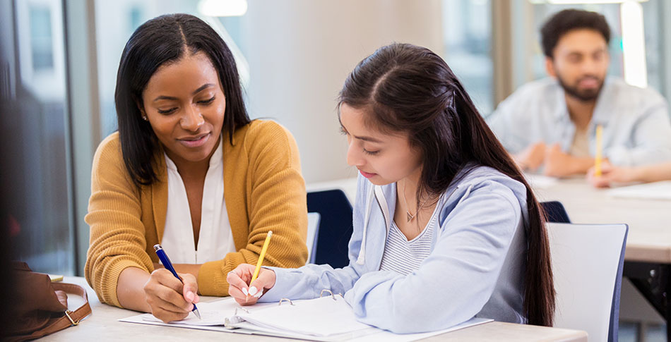 Person helping a student fill out something on paper