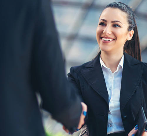 person in business attire shaking another persons hand who is also in business attire