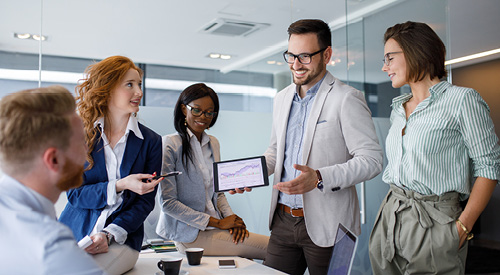 people standing around a person holding a tablet with graphs on it