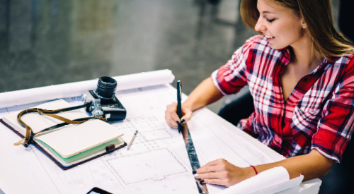 person with a ruler and pencil writing on building plans 