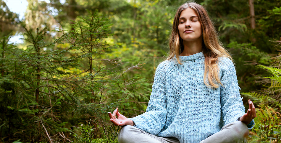 Person sitting in a forest meditating