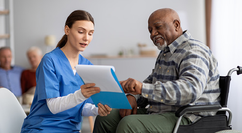 nurse showing a clipboard to a patient in a wheelchair