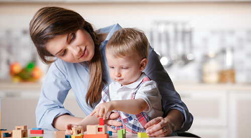 infant teacher working with an infant and blocks