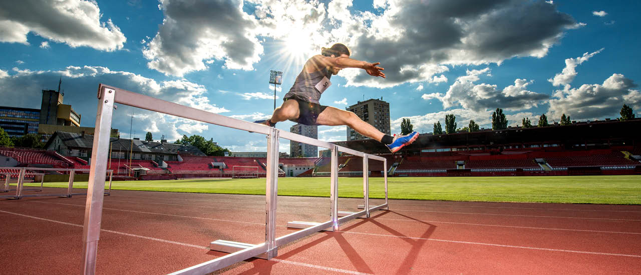person jumping over a hurdle on a track