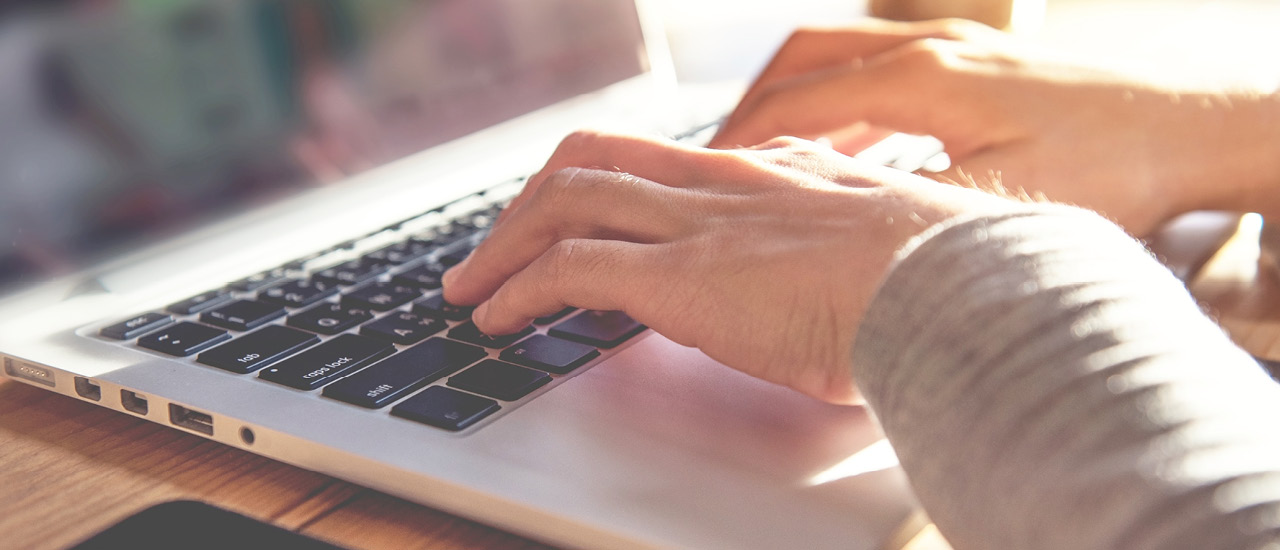 Hands typing on a laptop.