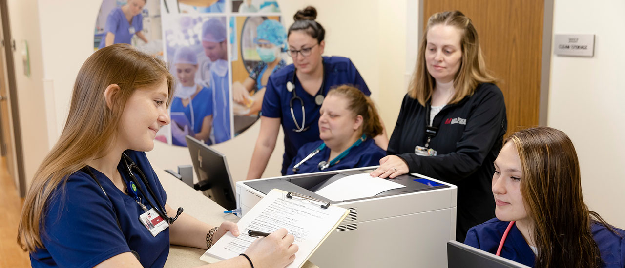 Healthcare students working at computers and with patient files