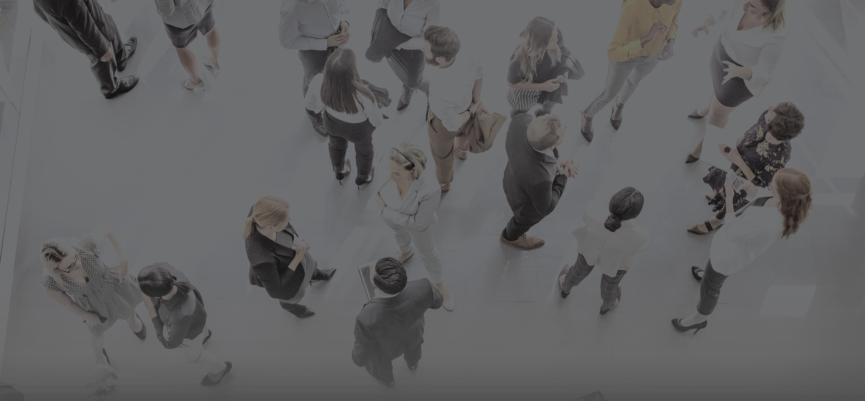 Birds eye view of a group of people standing conversing in a conference room 