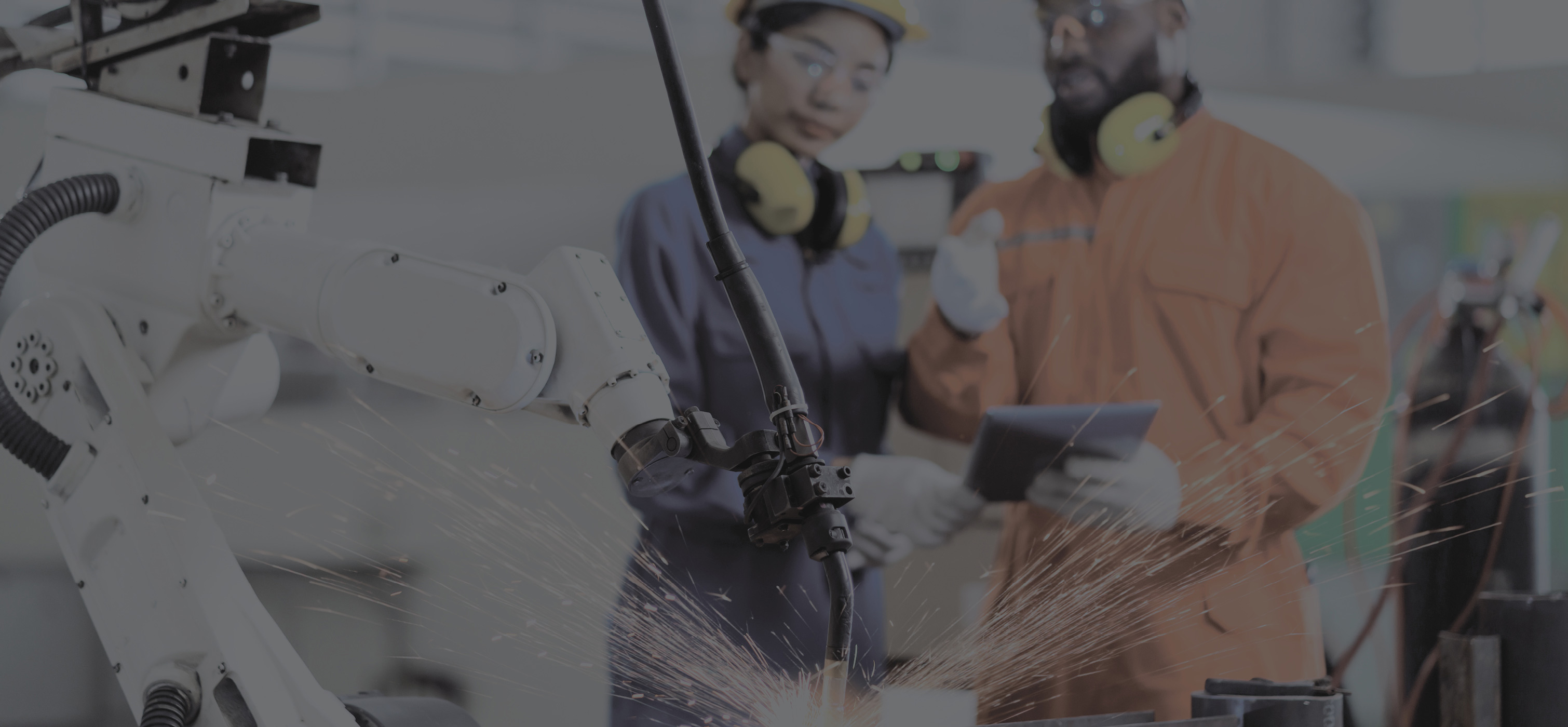 2 people with hardhats observing a machine welding