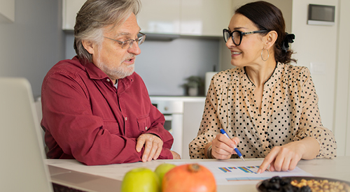 Person working with an elderly person showing them graphs 