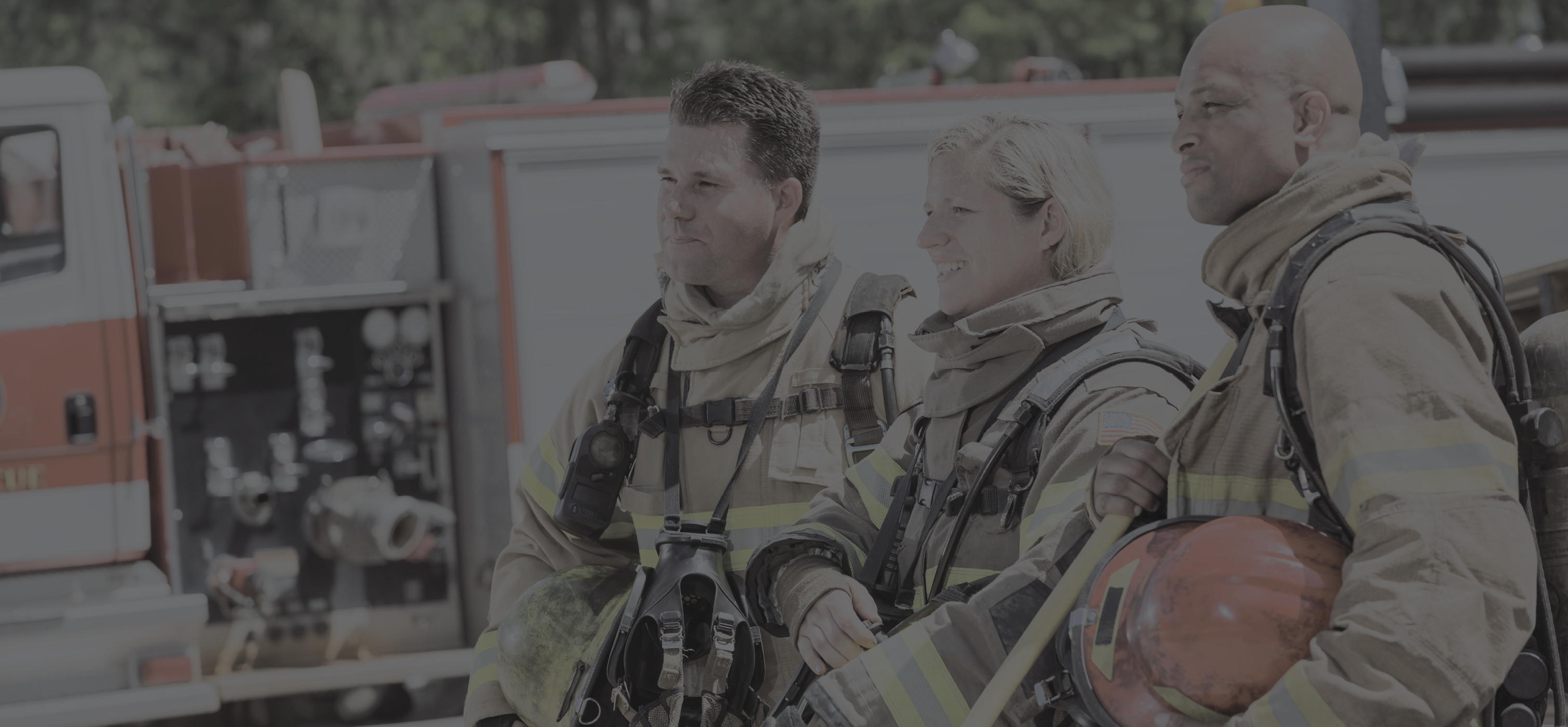 3 people dressed in firefighting gear standing next to a fire truck