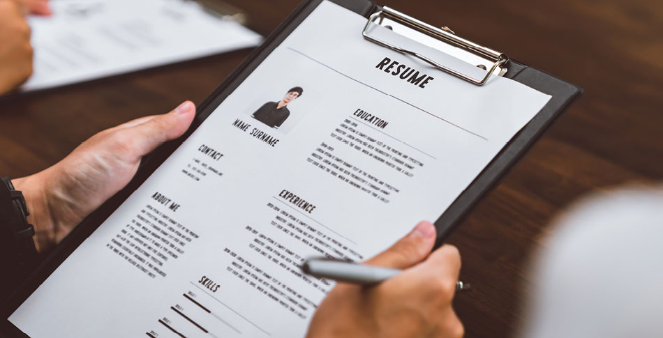 Person holding a resume on a clipboard.