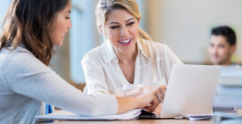 Two people pointing at a laptop and looking at the screen.