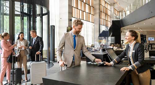 Front desk at a hotel. person is checking in while the person behind the counter helps them