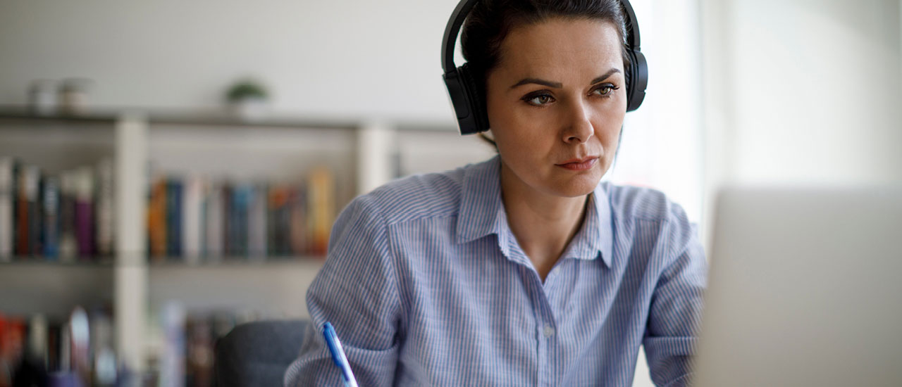 Woman working on a computer with headphones on.