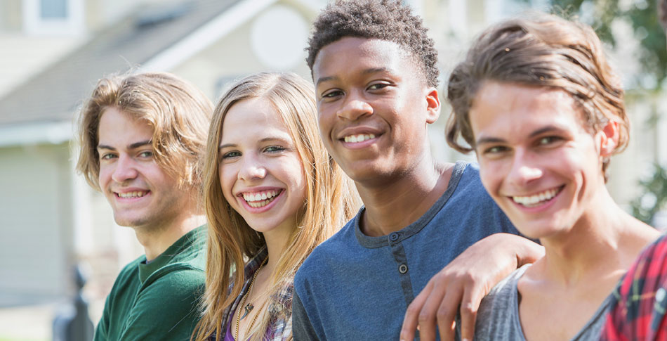 Four people standing in a line smiling.