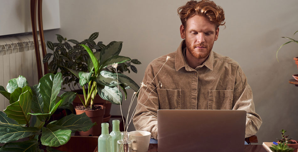 Man working on a laptop next to plants.