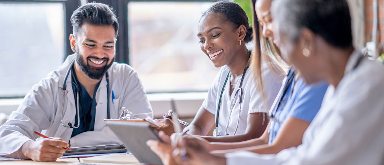 Doctors and nurses sit around a table.