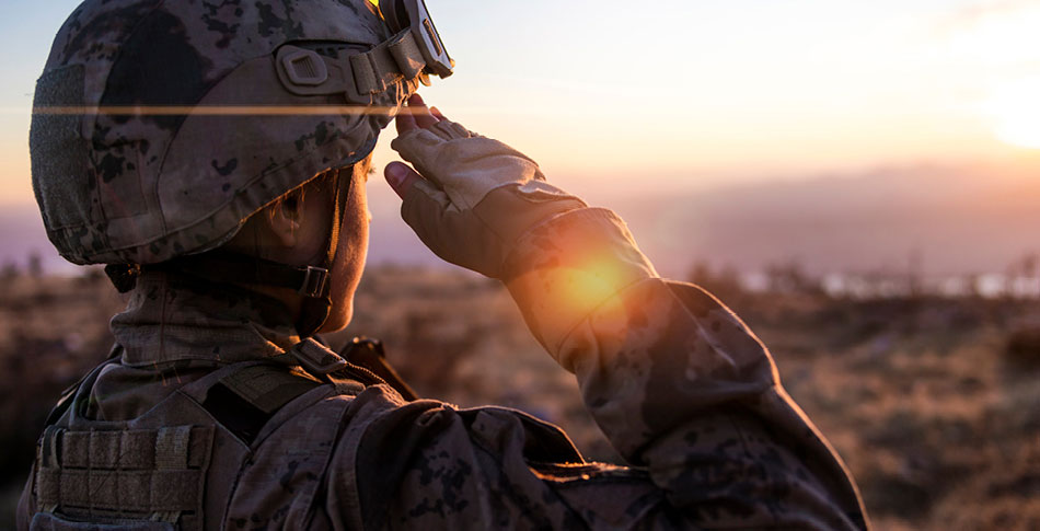 Member of the military saluting at sunset.