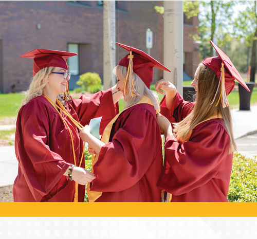 3 people in graduation gowns helping each other with their outfits