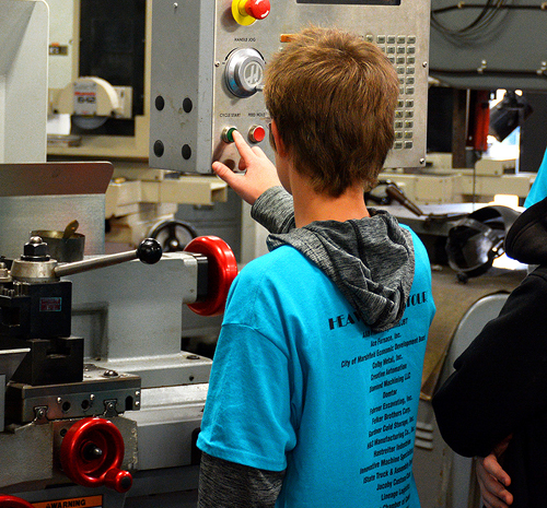 Student pressing a green button on a piece of machinery