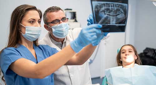 Dentist and Dental Hygienist looking at x-rays of a persons mouth