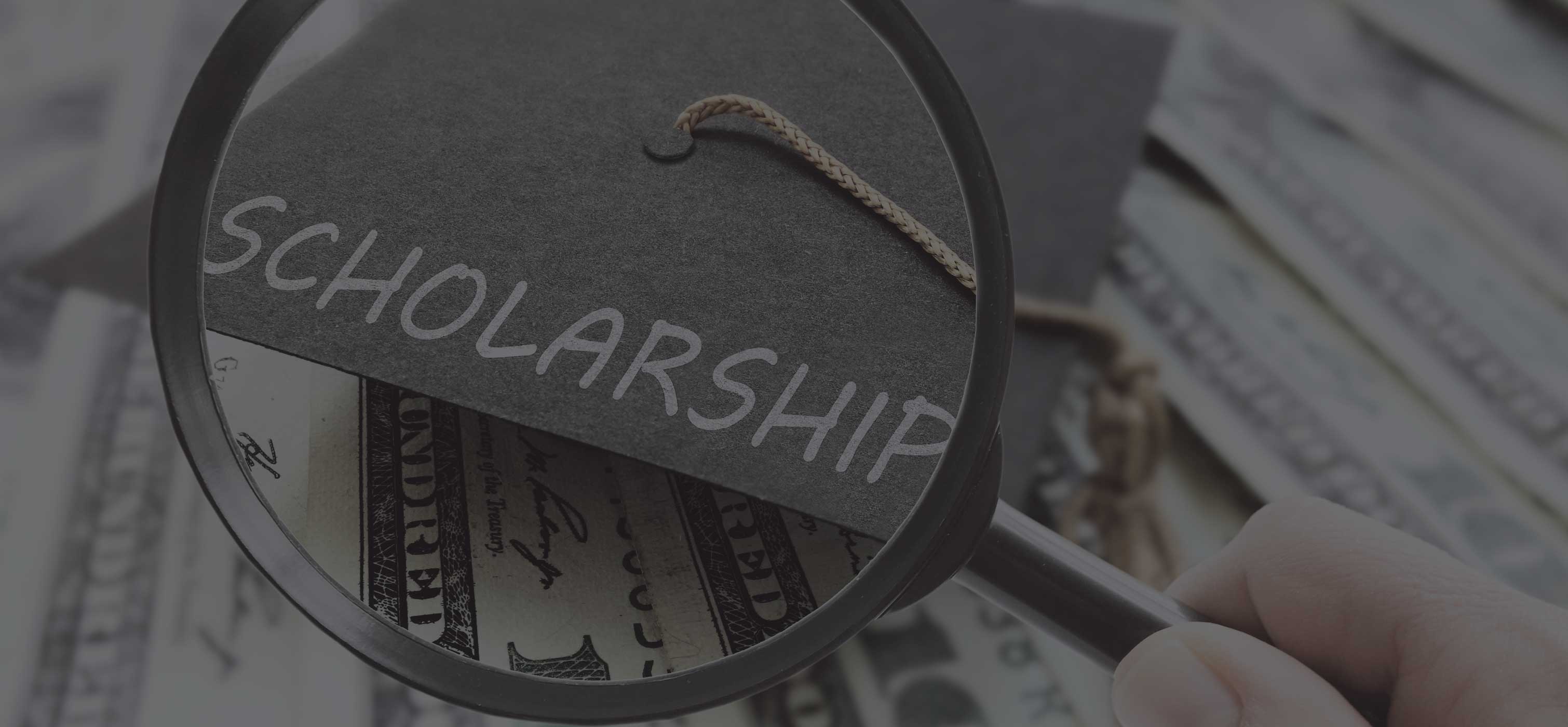 Magnifying glass held over a graduation cap that says Scholarship on it with a background of $100 bills