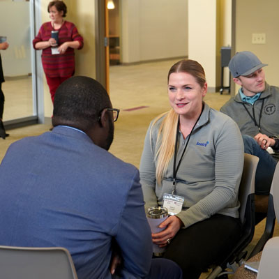 Two people sit facing each other, engaged in conversation