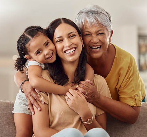 Image of a daughter, mom, and grandmother smiling looking at the camera