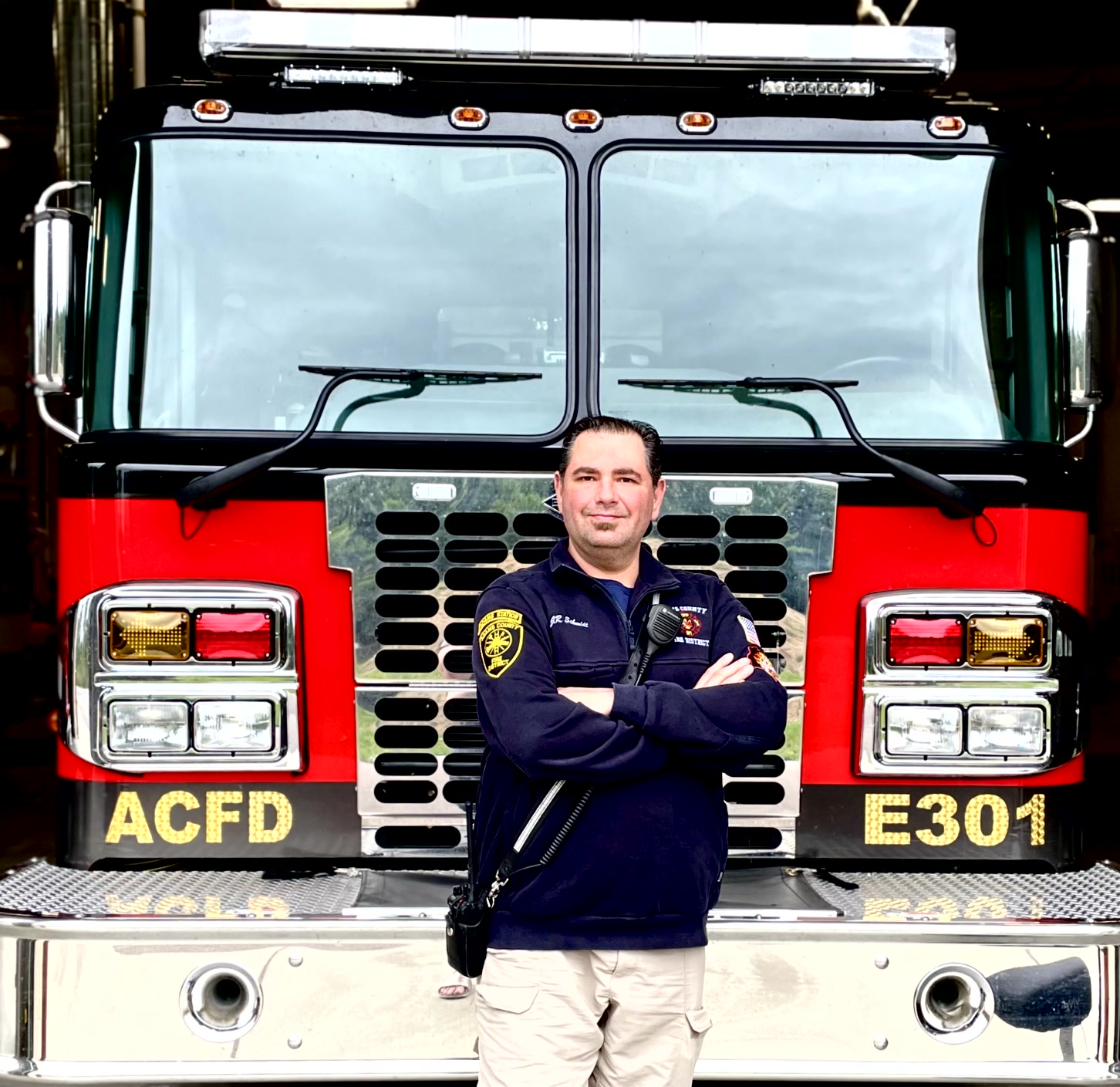 J.R. Schmidt standing in front of a firetruck, wearing his uniform