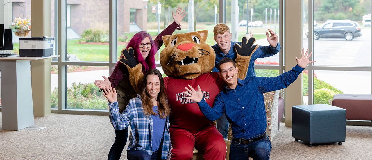 Four Mid-State students surround Mid-State's mascot, Grit.